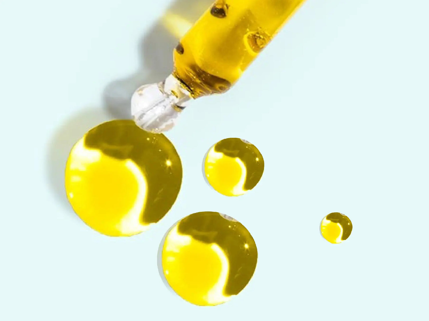 Pipette and drops showing the golden color of the CBD oil
